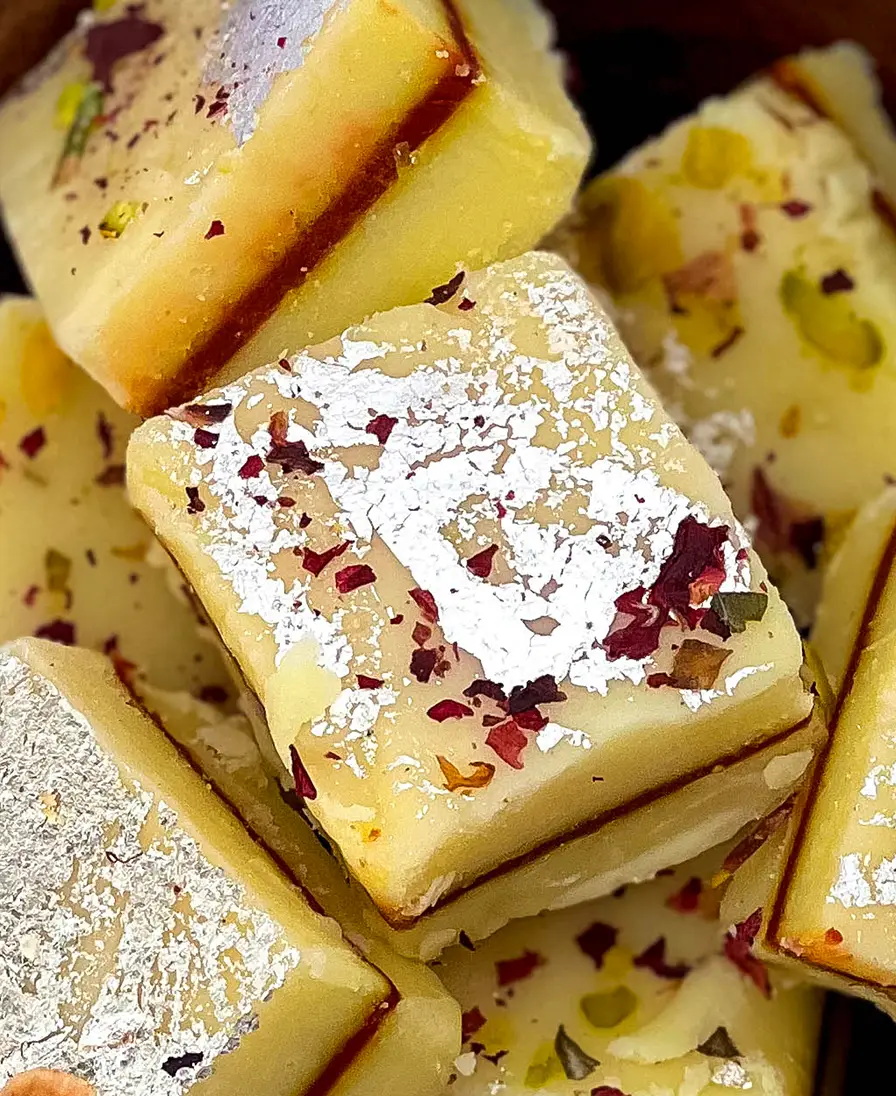 Mithai selection Close-up of silver-leaf topped mithai with rose petals and pistachio.